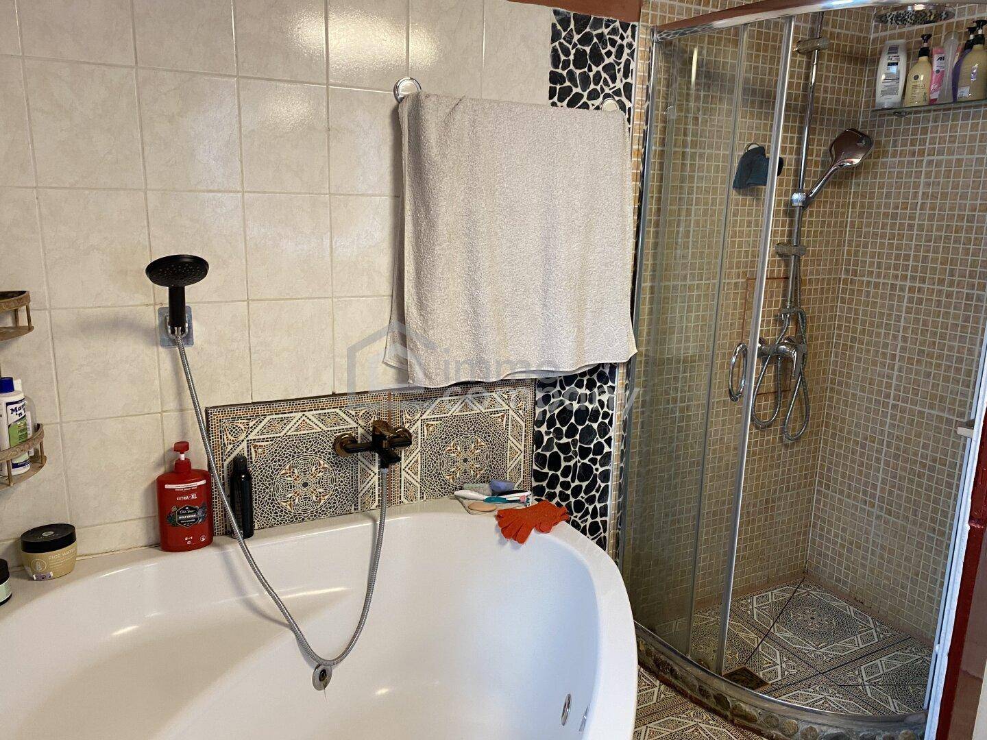 Badezimmer mit Badewanne, separater Duschkabine und gemusterten Fliesen im mediterranen Stil.
