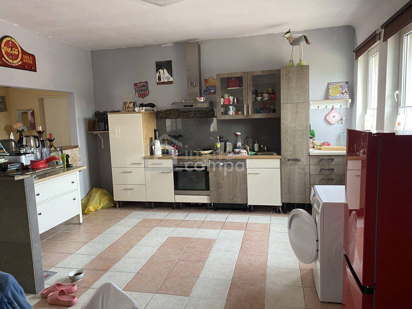 Funktionale Küche mit Einbauschränken, Waschmaschine und großem Fenster.