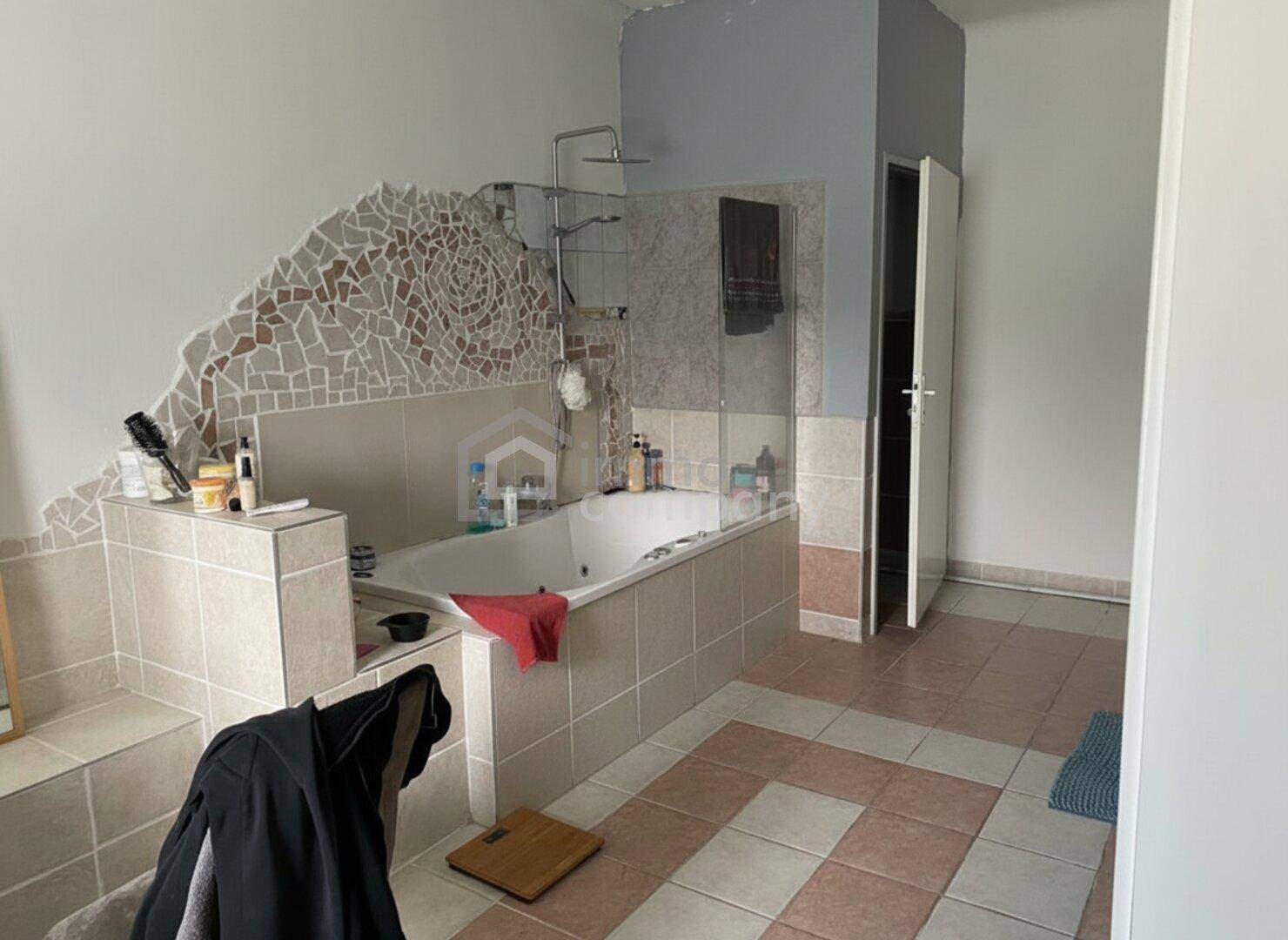 Geräumiges Badezimmer mit Badewanne, Duschbereich und dekorativen Mosaikfliesen an der Wand.