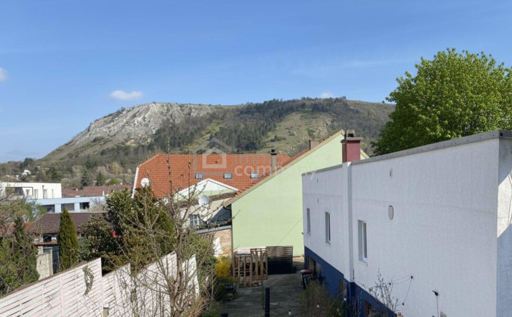 Weitläufiger Blick über Dächer und eine hügelige Landschaft mit einem fernen Berg.