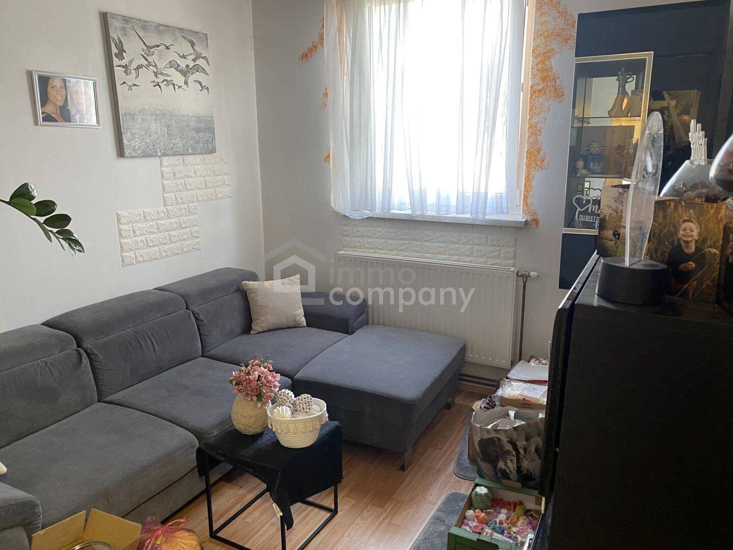 Wohnzimmer mit bequemem Ecksofa, Laminatboden und dekorativen Wandelementen.