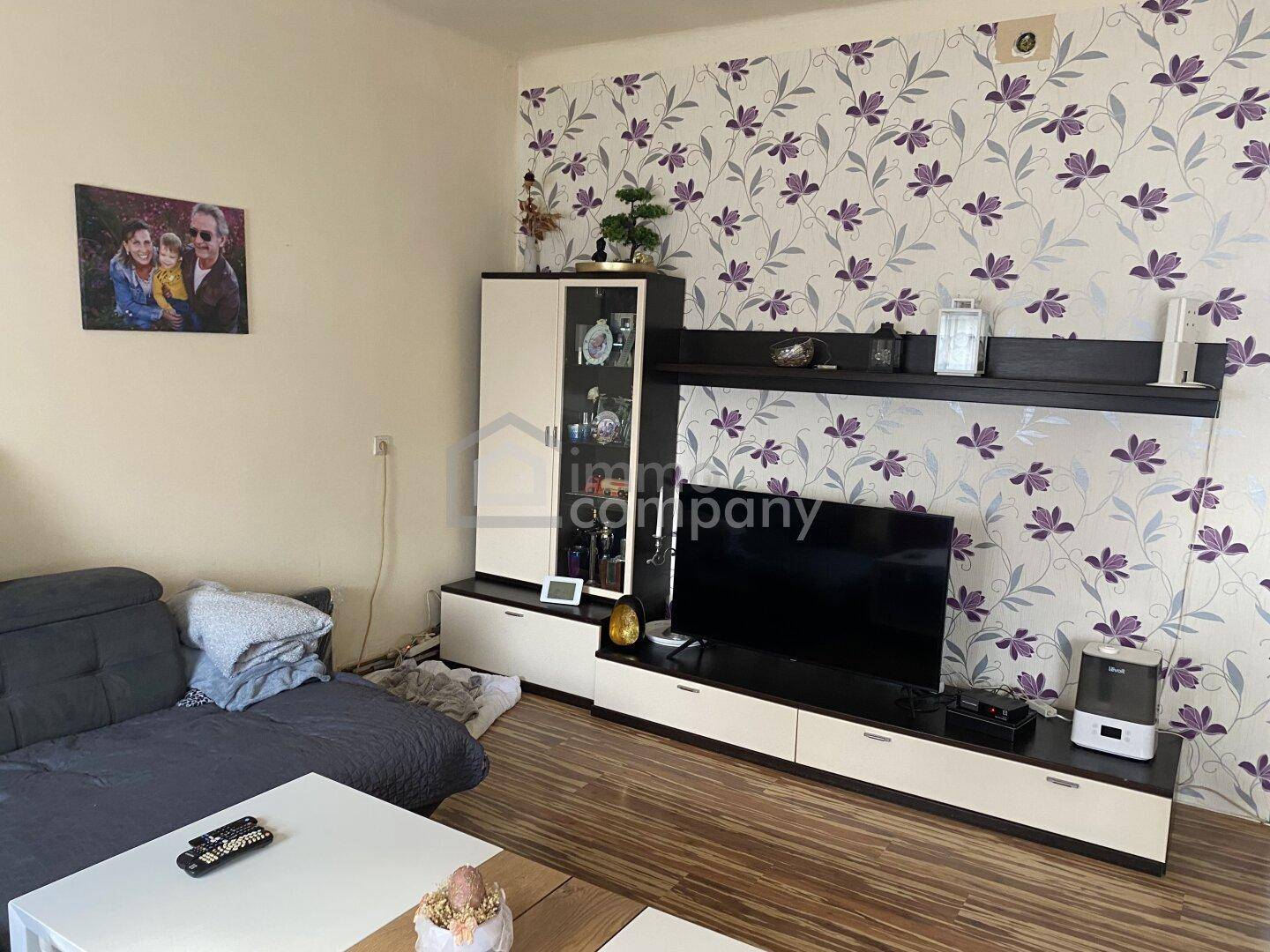 Wohnzimmer mit floraler Tapete, TV-Möbeln und einem bequemen Sofa für Unterhaltung.