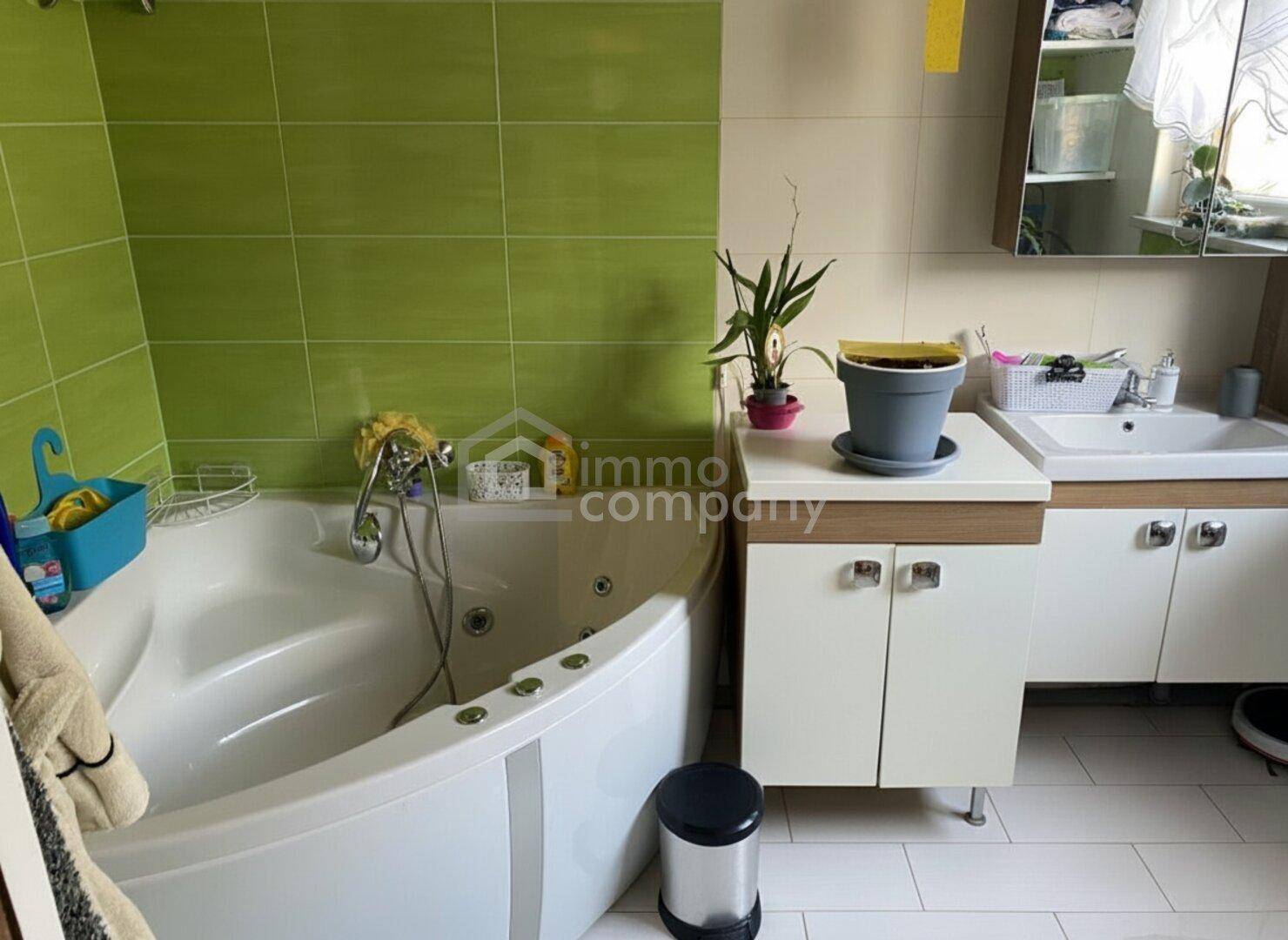 Badezimmer mit Eckbadewanne und grünen Wandfliesen, bietet eine entspannende Atmosphäre.