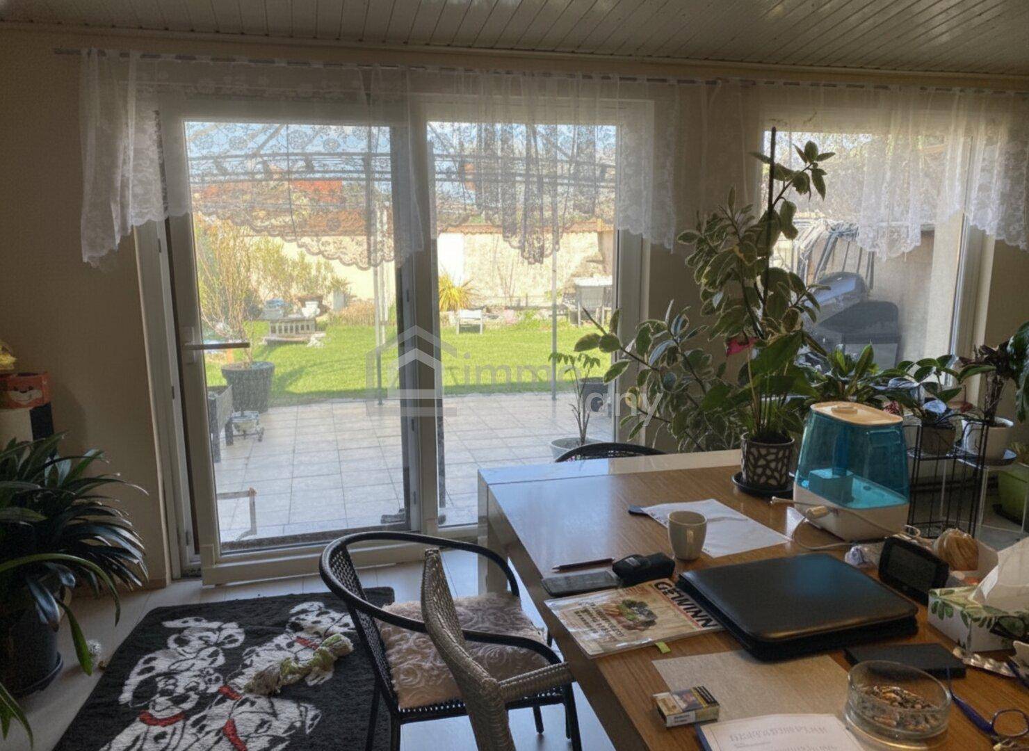 Heller Innenraum mit großen Fenstern und direktem Zugang zur Terrasse und zum Garten.