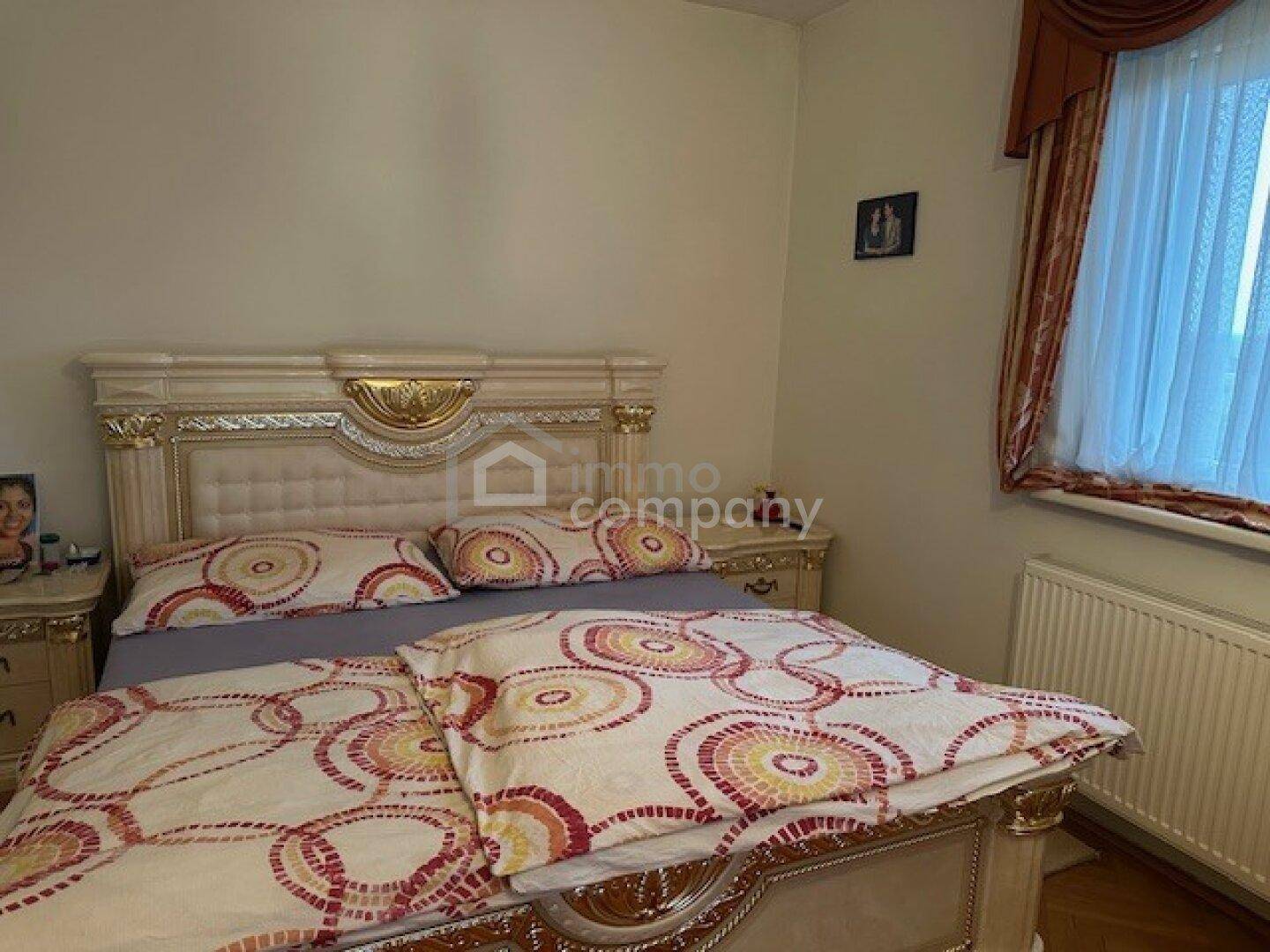 Schlafzimmer mit opulentem Doppelbett, gemustertem Bettzeug und Fenster.