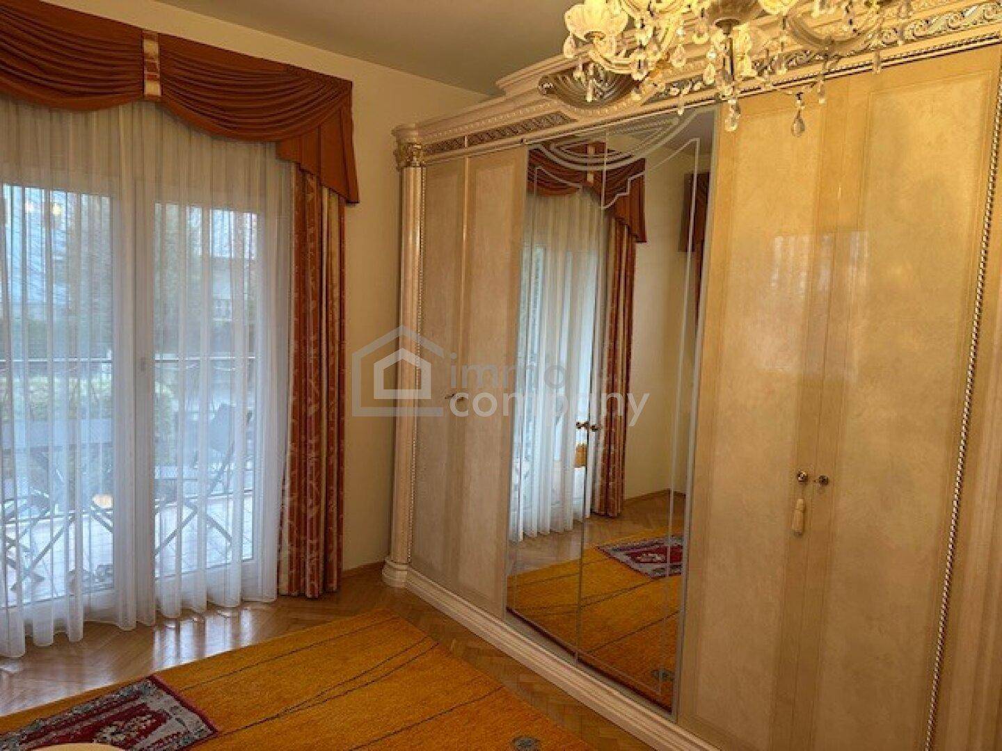 Schlafzimmer mit großem Spiegelschrank und Zugang zu einem Balkon oder einer Terrasse.