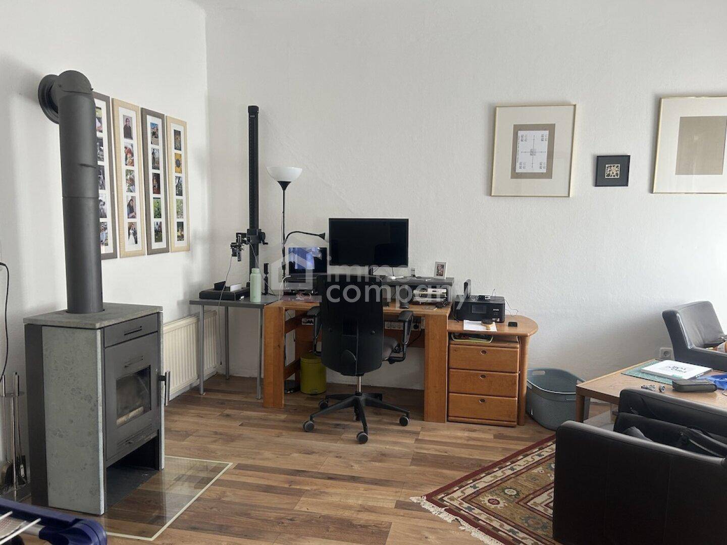 Wohnbereich mit Holzboden, Kaminofen und einem Arbeitsplatz mit Schreibtisch.