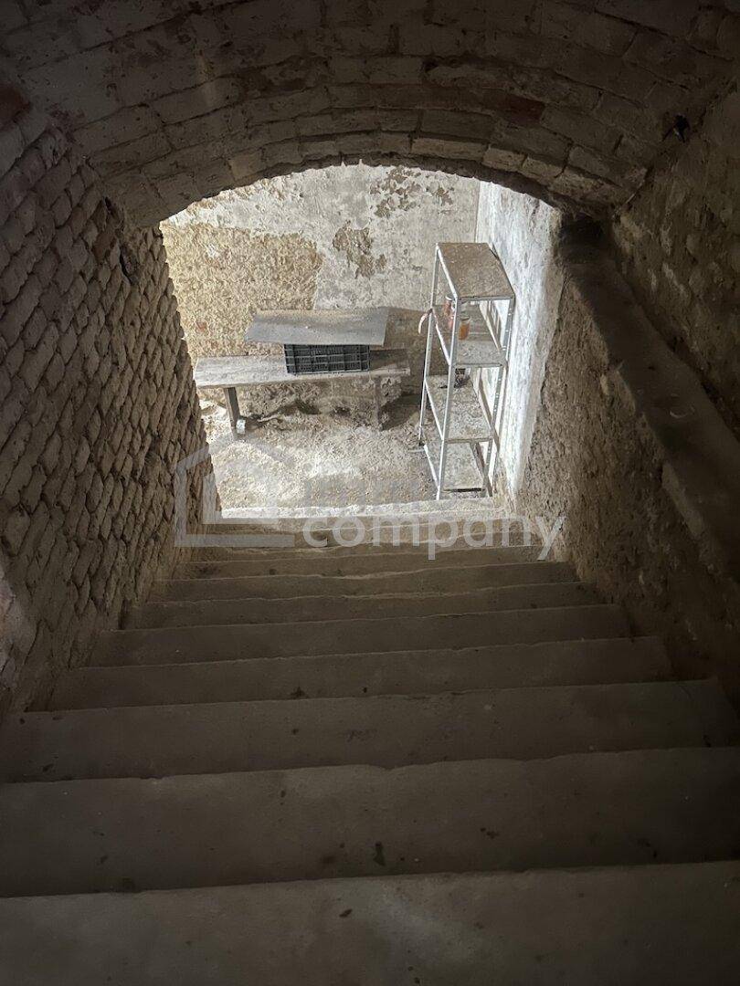 Steile Kellertreppe führt hinunter in einen unverputzten Gewölbekeller.