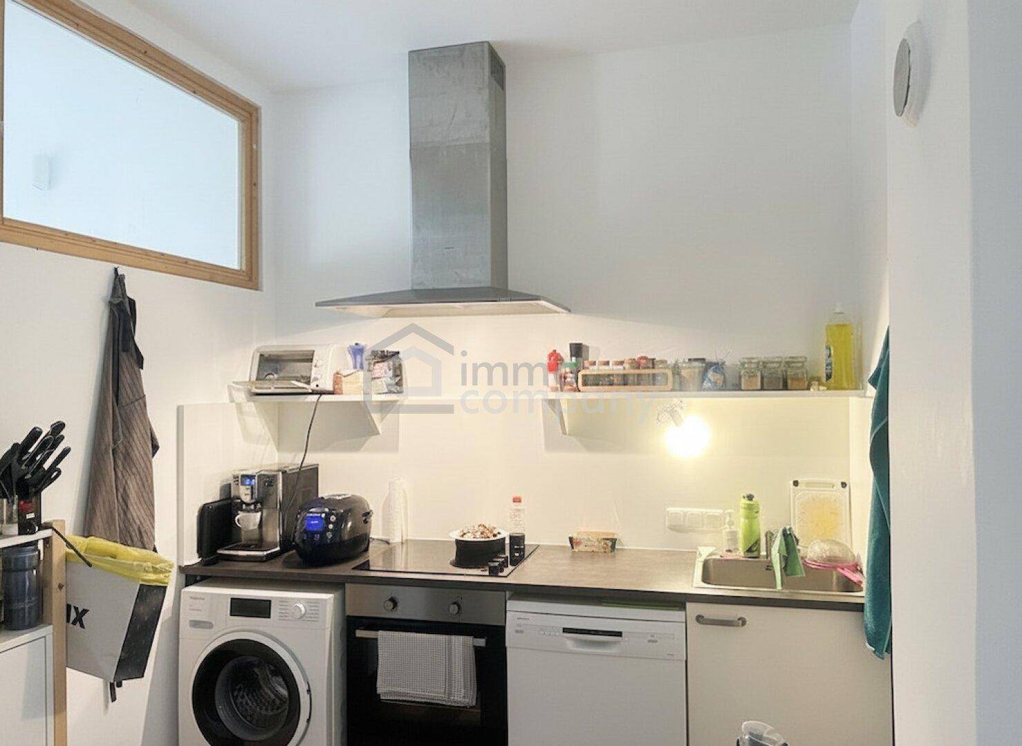Funktionale Küche mit modernen Geräten, weißen Schränken und einem Fenster.