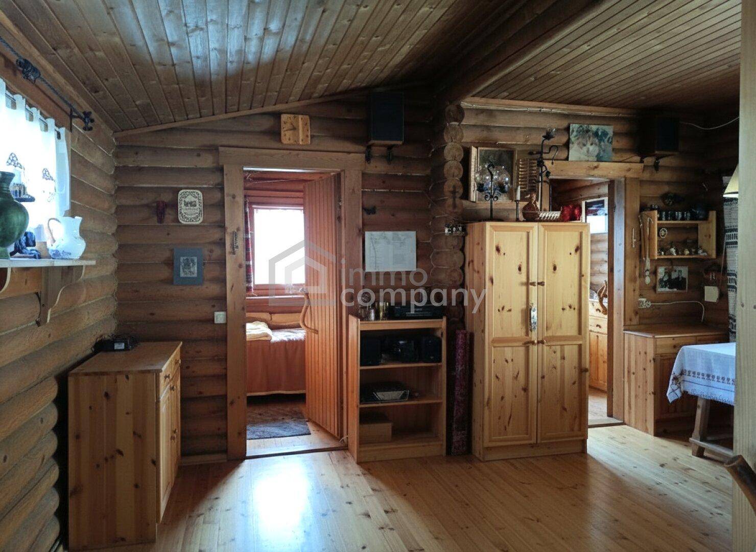 Gemütlicher Wohnraum mit Holzböden, Holzmöbeln und sichtbaren Holzbalken an der Decke.