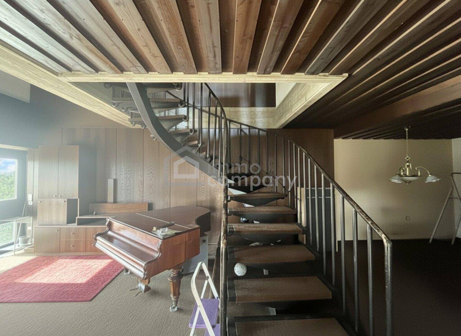 Geräumiger Wohnbereich mit offener Wendeltreppe, Holzbalkendecke und Klavier.