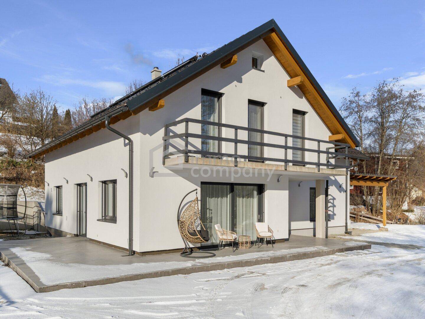Modernes Einfamilienhaus mit Terrasse, Balkon und schneebedecktem Gartenbereich.