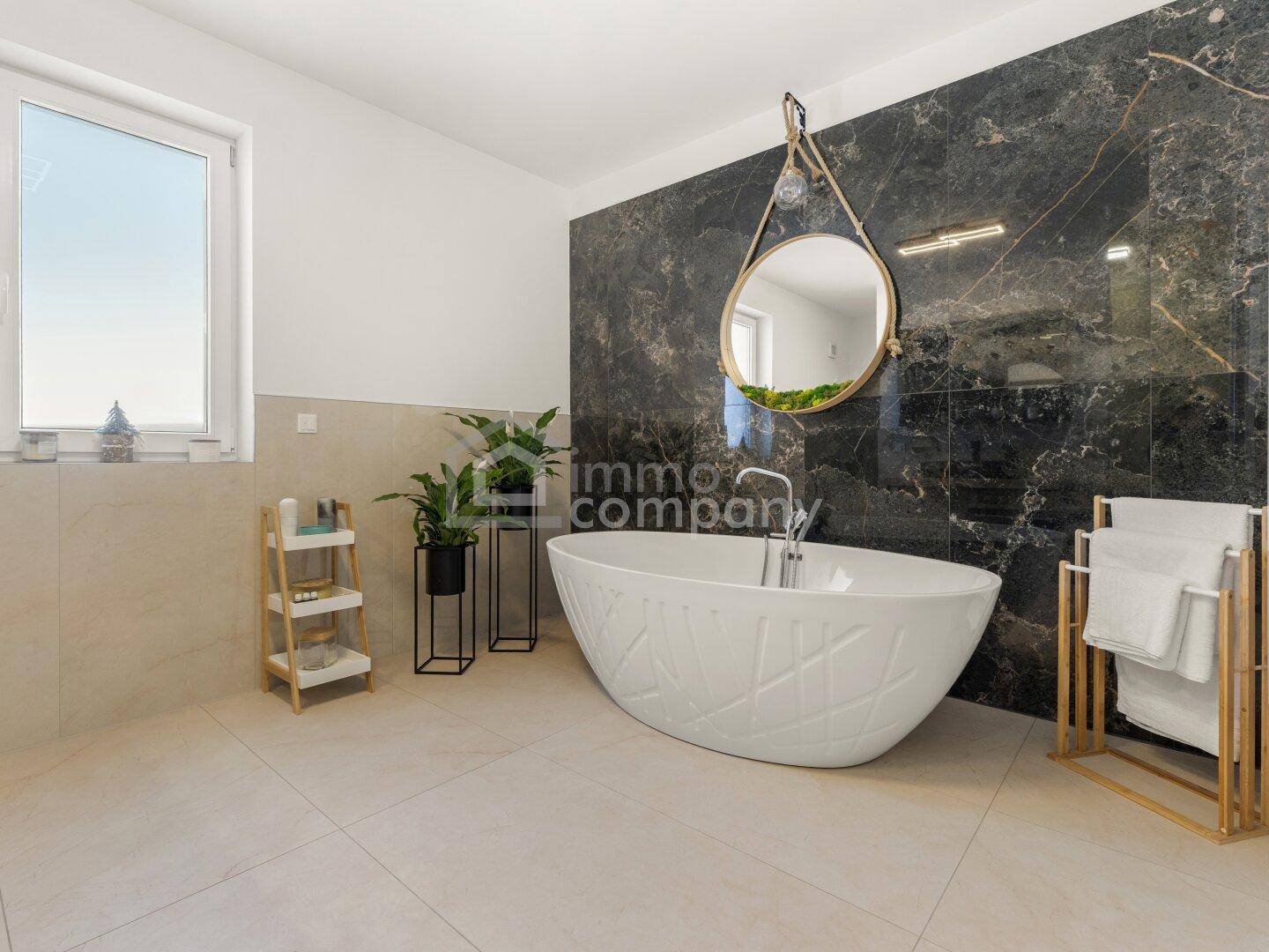 Elegantes Badezimmer mit freistehender Badewanne, dunkler Marmorwand und Fenster.