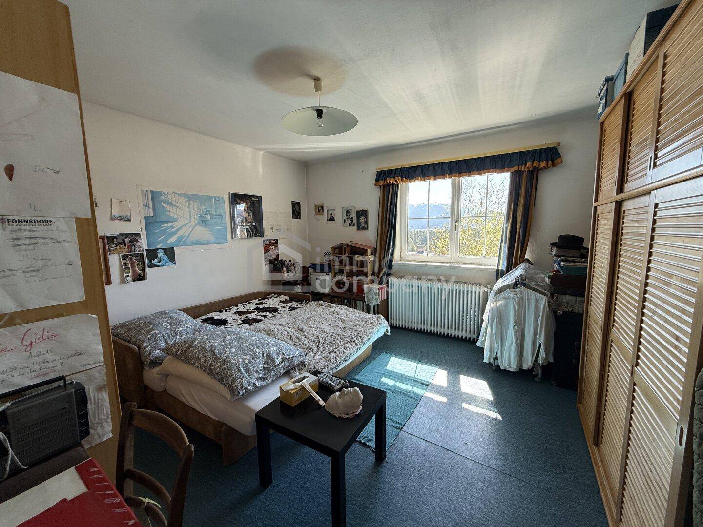 Schlafzimmer mit blauem Boden, großem Kleiderschrank und Fenster mit Bergblick.