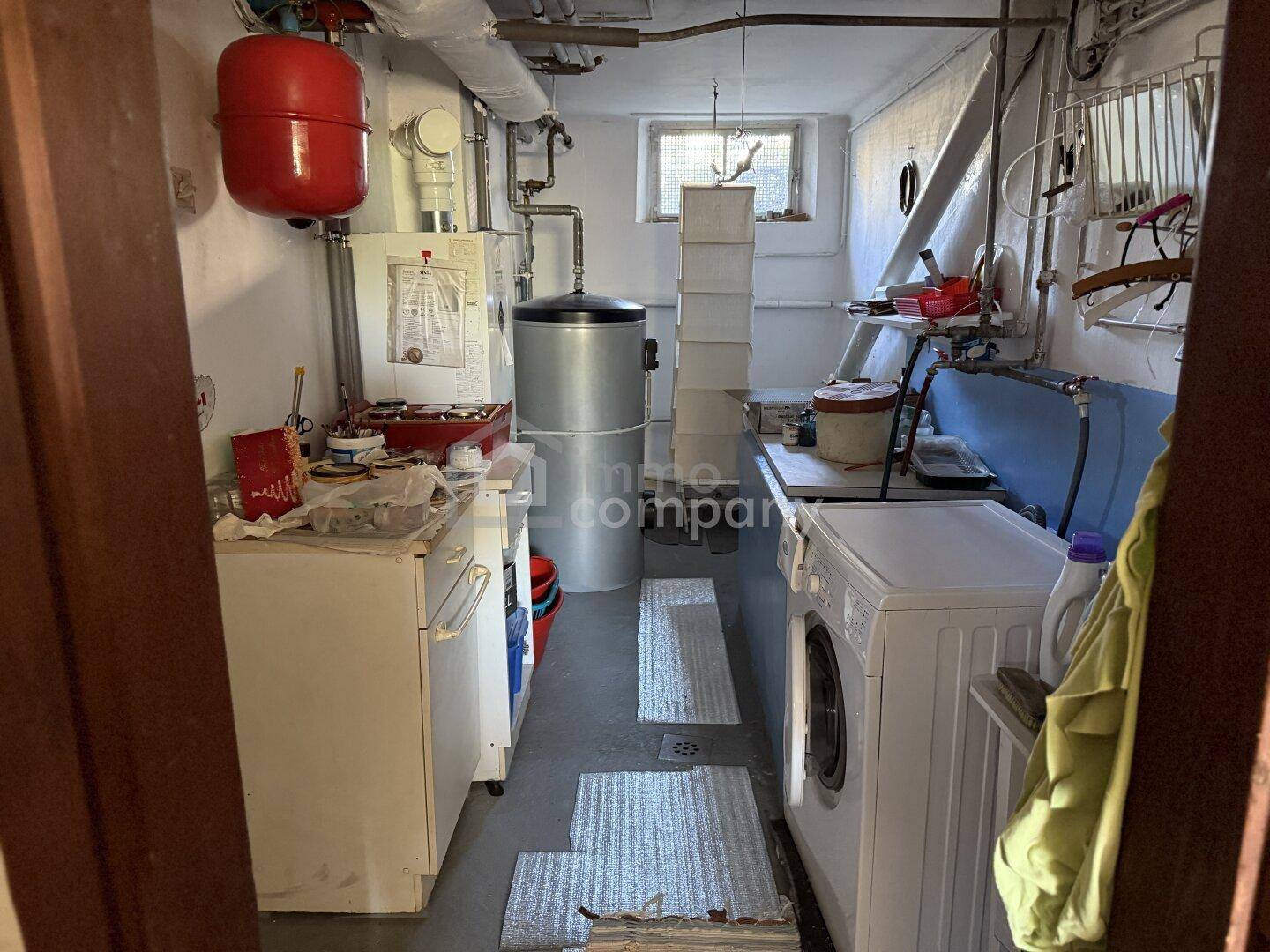 Hauswirtschaftsraum im Keller mit Waschmaschine, Boiler und Heizungsinstallationen.
