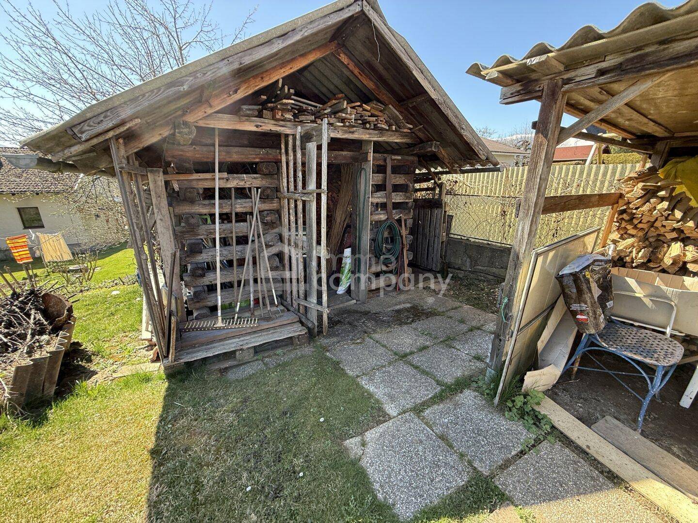 Rustikaler Holzschuppen im Garten, genutzt zur Lagerung von Holz und Gartengeräten.