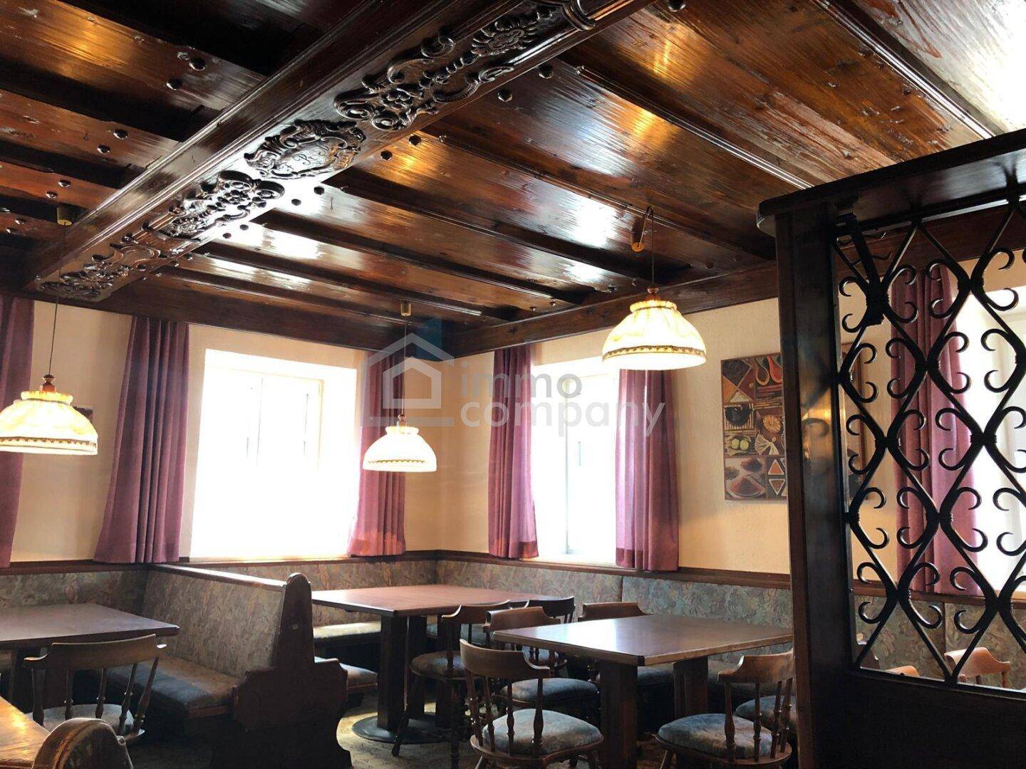 Gemütlicher Gastraum mit dunkler Holzdecke, geschnitzten Details und traditionellen Sitzbänken.