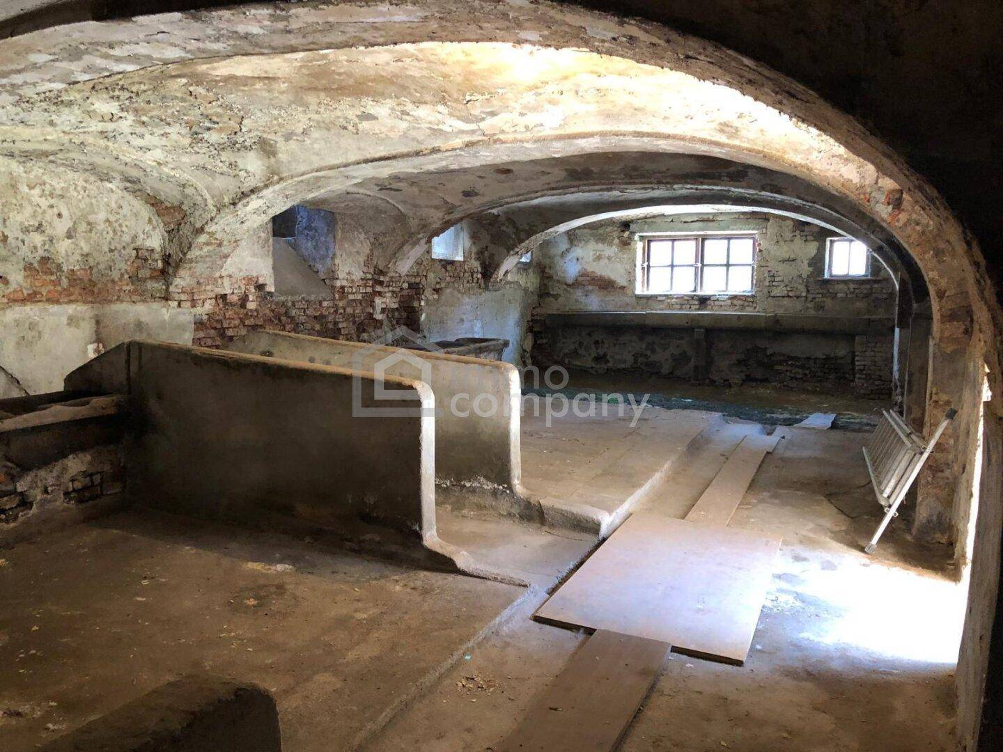 Unfertiger Kellerraum mit Ziegelgewölben, Betonstrukturen und kleinen Fenstern.