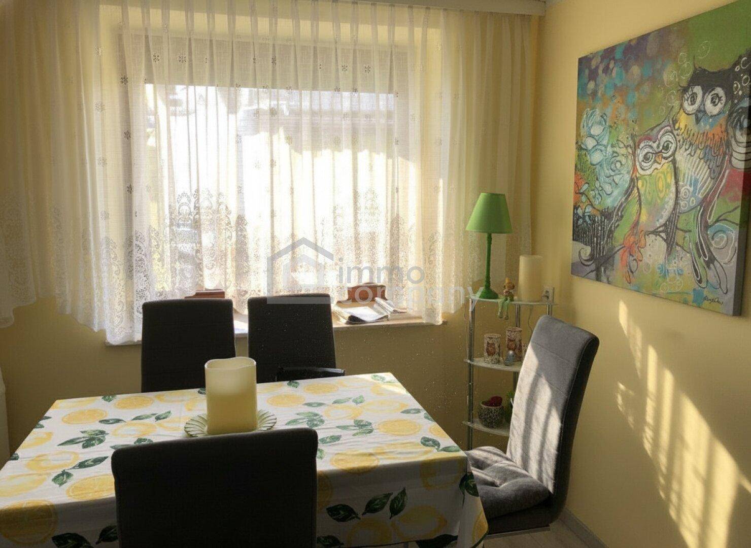 Heller Essbereich mit gelben Wänden, einem Esstisch und Blick ins Grüne durch das Fenster.