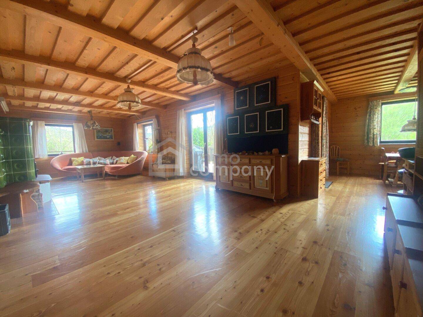 Gemütliches Wohnzimmer im Landhausstil mit Holzböden, Holzdecken und einem traditionellen Kachelofen.