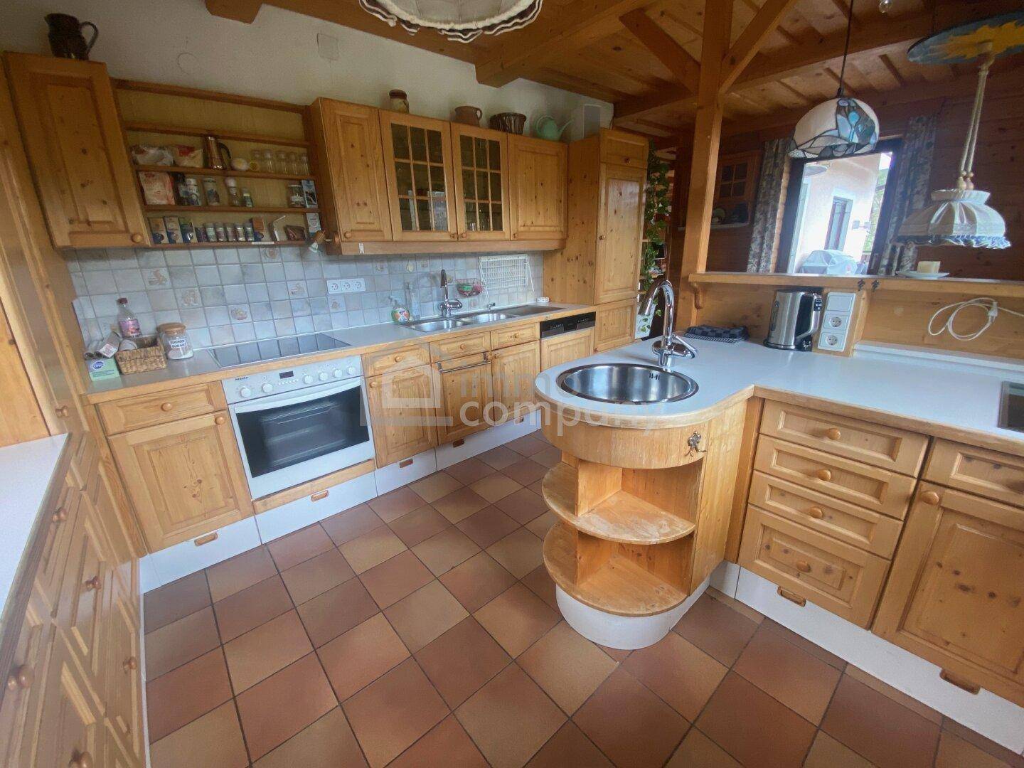 Voll ausgestattete Holzküche mit Spülbecken, Herd und traditionellen Fliesen.