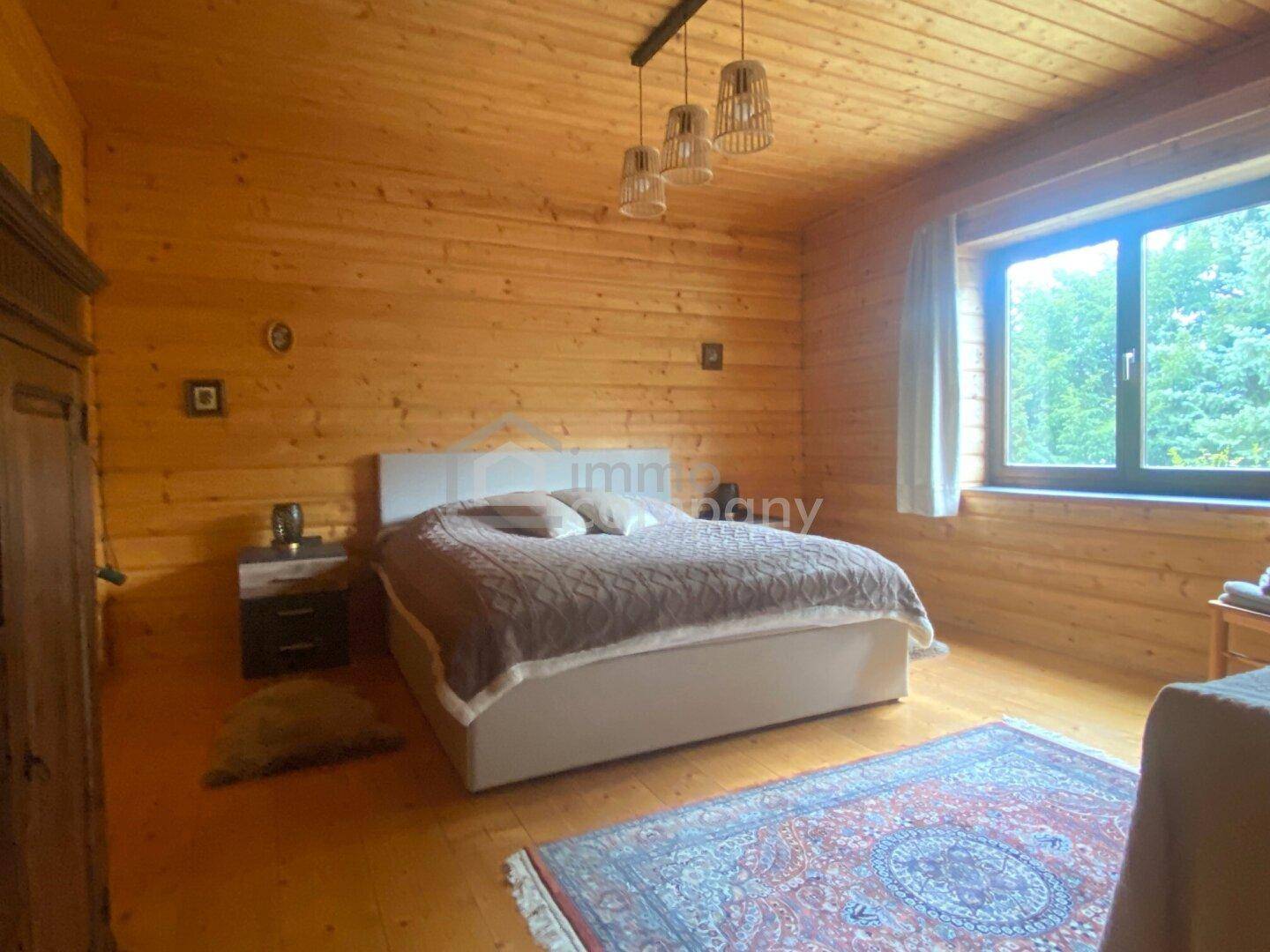 Gemütliches Schlafzimmer mit Holztäfelung an Wänden und Decke sowie Holzboden.