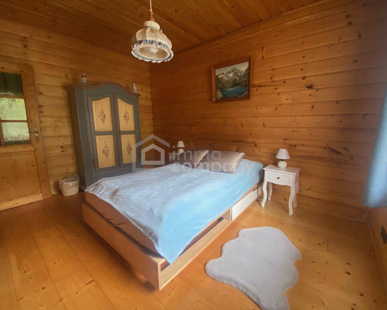 Helles Schlafzimmer mit Holzwänden, Holzboden und einem Einzelbett.