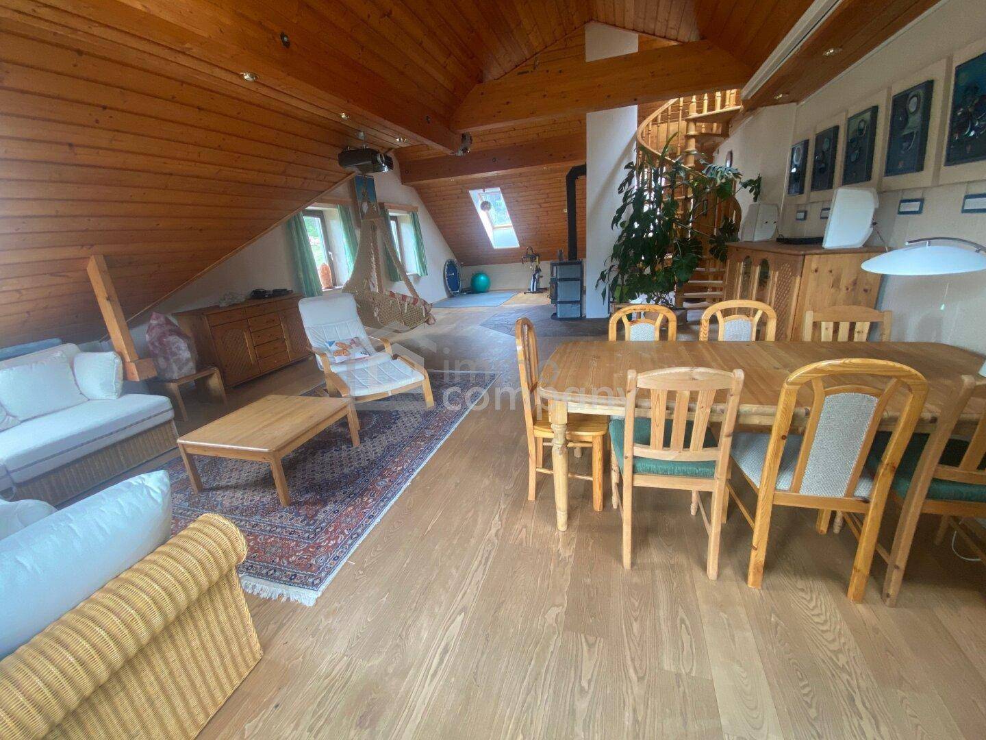 Geräumiger Wohn- und Essbereich im Dachgeschoss mit Holzboden und viel Tageslicht.