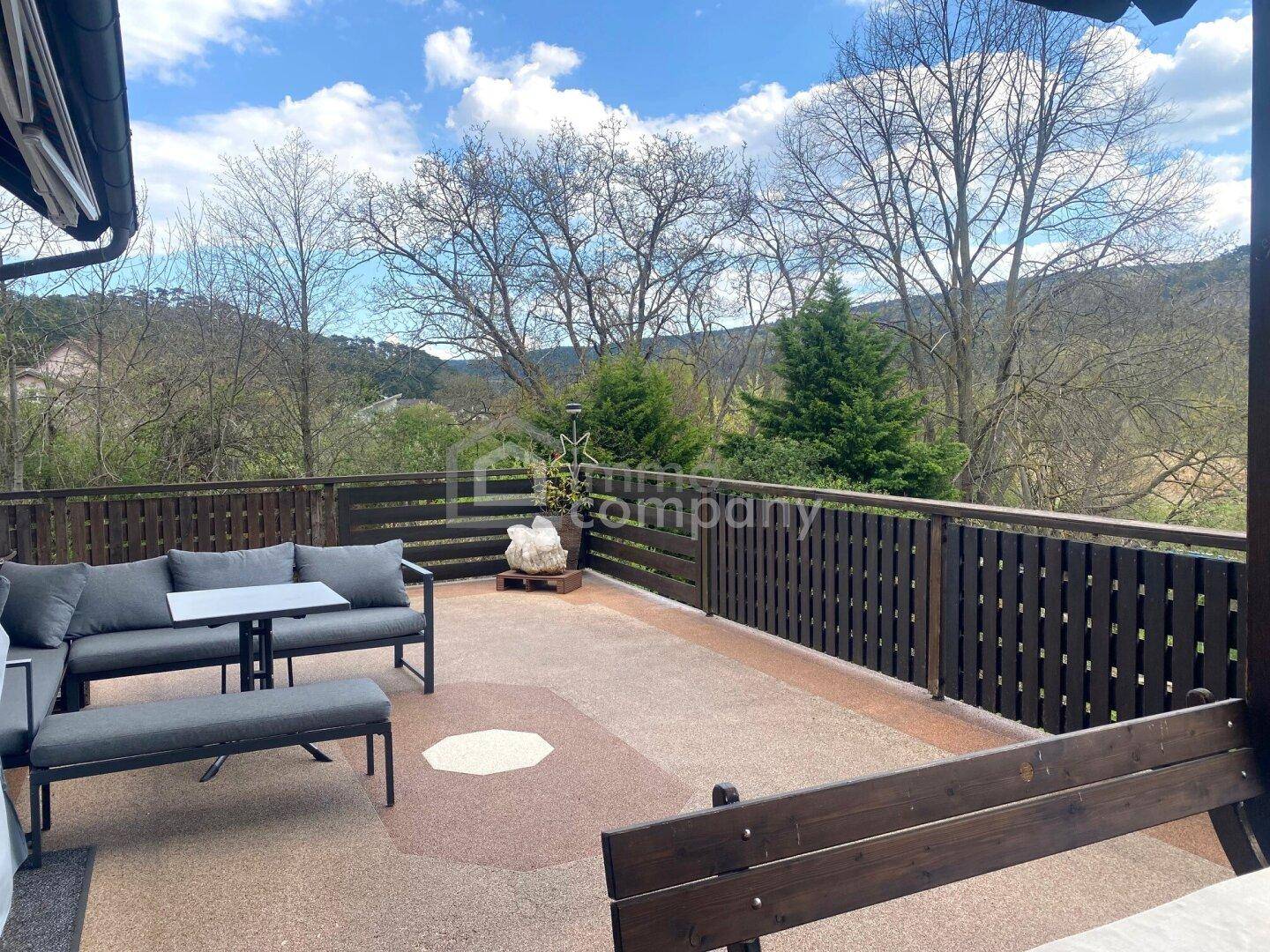 Geräumige Terrasse mit Sitzgelegenheiten und weitem Blick ins Grüne und auf die Hügel.