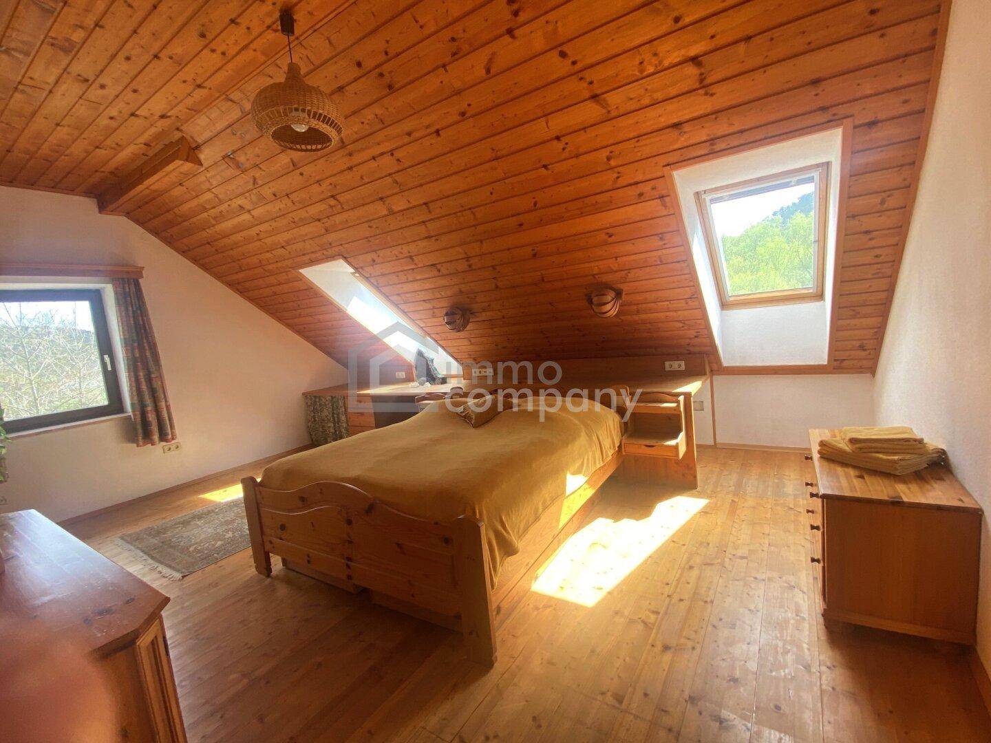 Gemütliches Schlafzimmer im Dachgeschoss mit Holzboden, Dachfenstern und Holztäfelung.