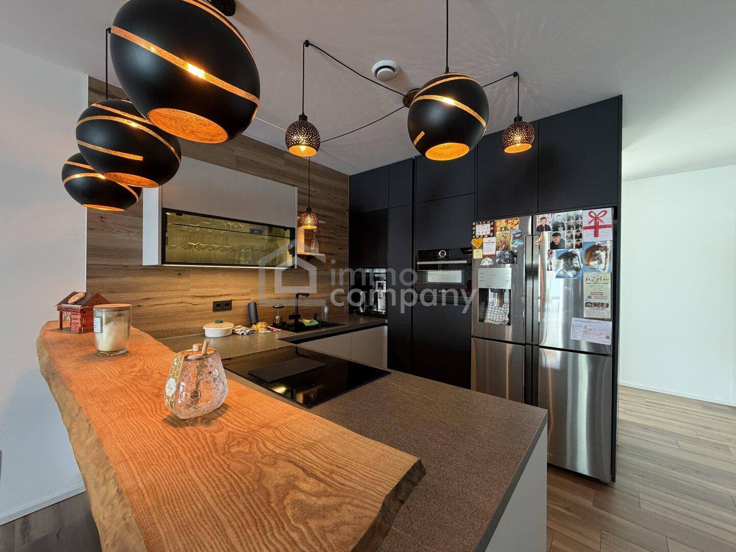 Moderne Küche mit dunklen Schränken, Holzdetails und einer Kücheninsel mit Kochfeld.