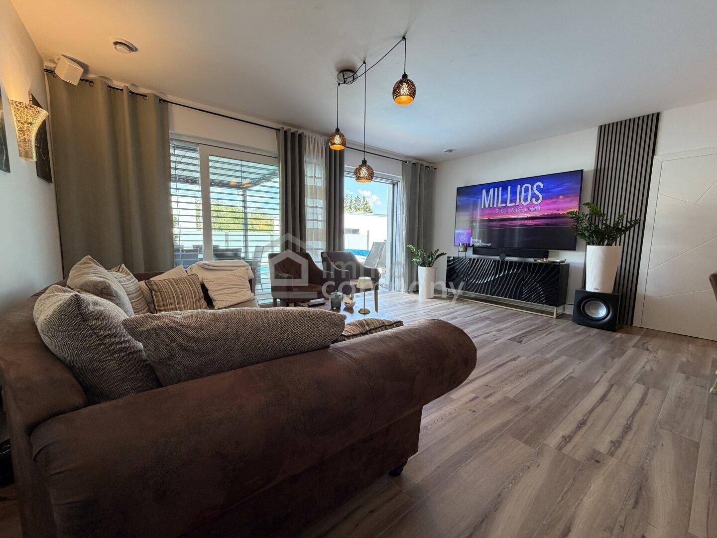 Gemütliches Wohnzimmer mit großem Sofa, Fernseher und Zugang zur Terrasse.