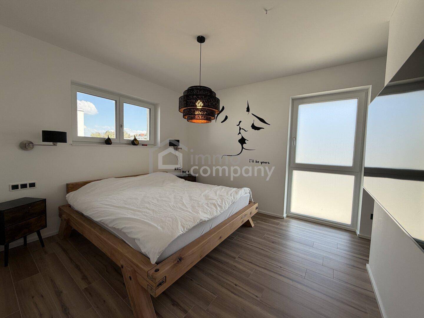 Helles Schlafzimmer mit Holzbett, großen Fenstern und modernem Dekor an der Wand.