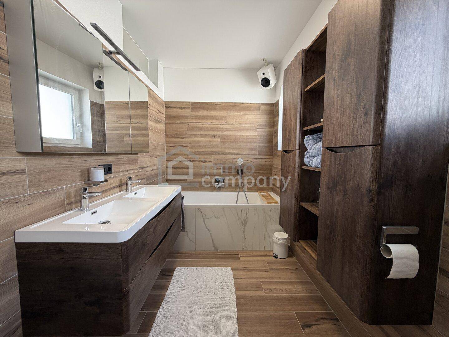 Modernes Badezimmer mit Doppelwaschbecken, Badewanne und Holzverkleidung.