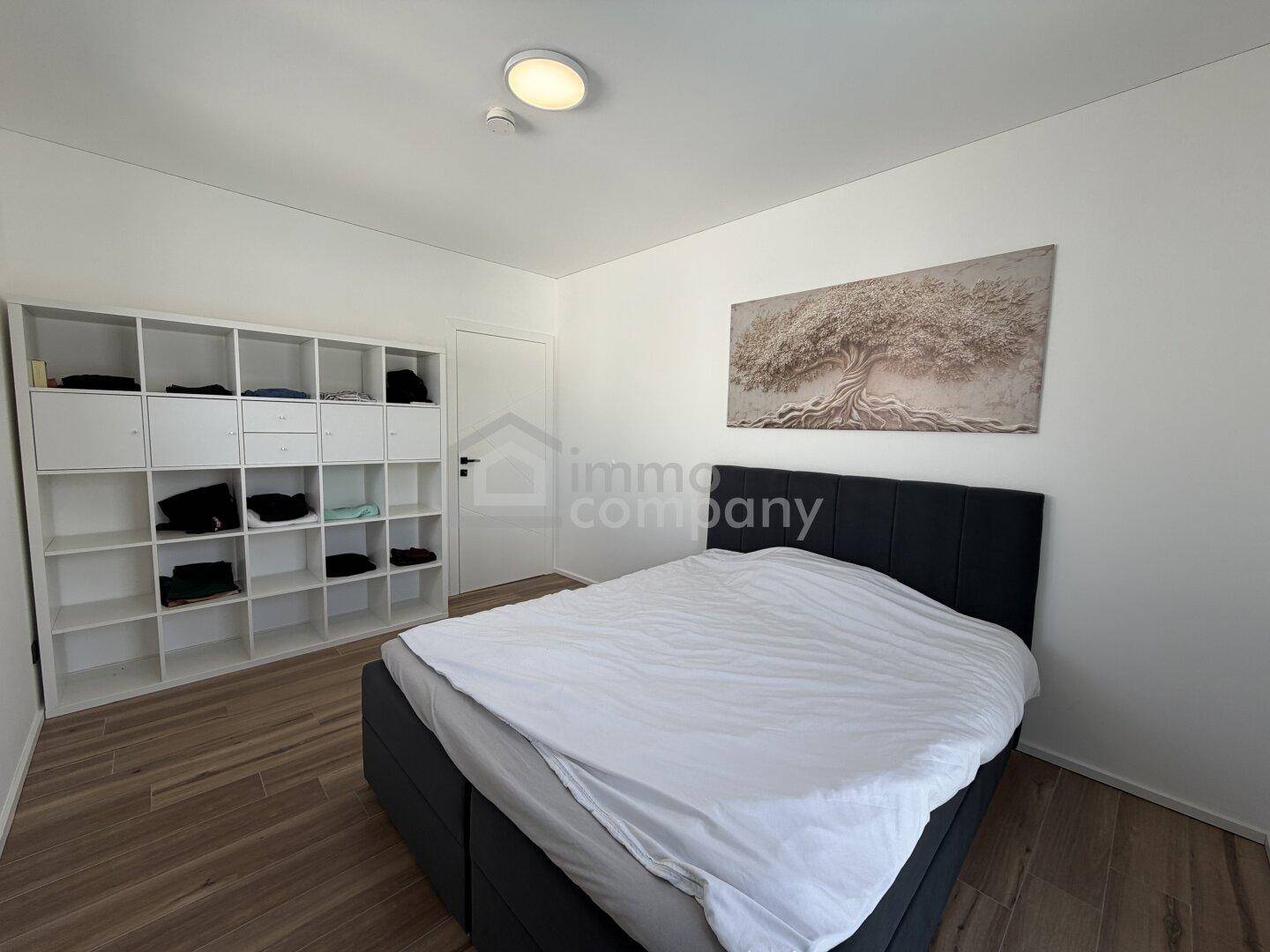 Helles Schlafzimmer mit Doppelbett und praktischem Regal für Stauraum.