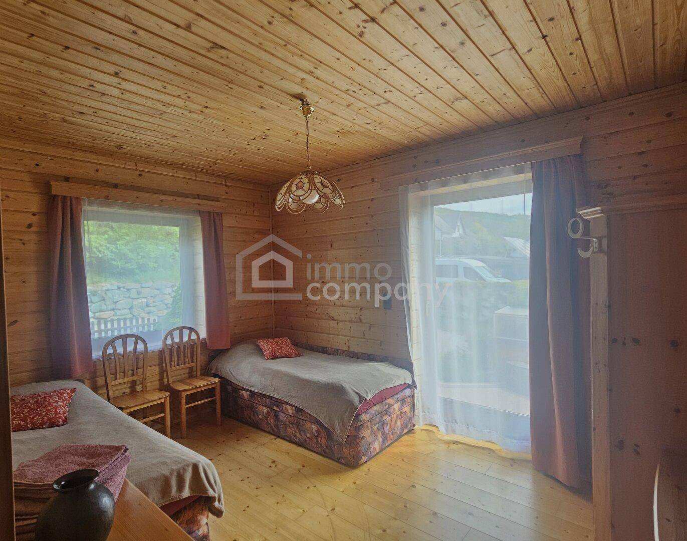 Schlafzimmer mit Holzwänden, Holzboden und Zugang zu einem Außenbereich.