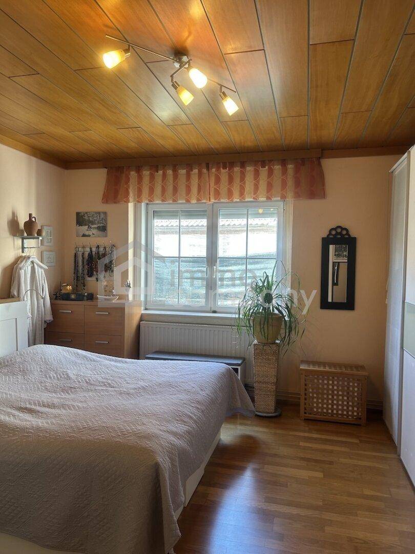 Schlafzimmer mit Holzboden, Holzdecke und einem Fenster mit Blick nach draußen.