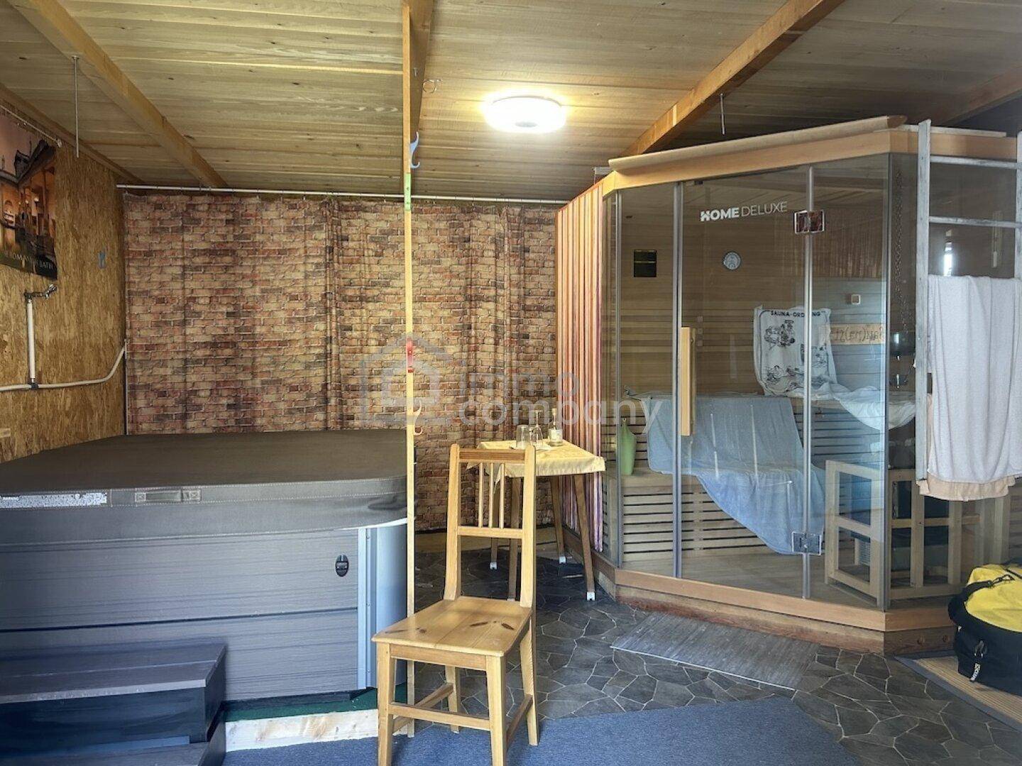 Entspannungsbereich mit Whirlpool und Sauna in einem rustikalen Raum mit Holzverkleidung.