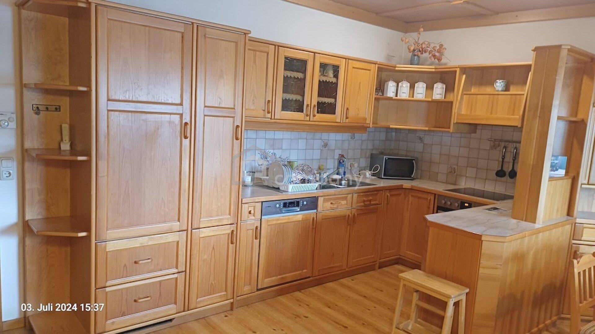 Voll ausgestattete Holzküche mit vielen Schränken, Spülmaschine und Mikrowelle.