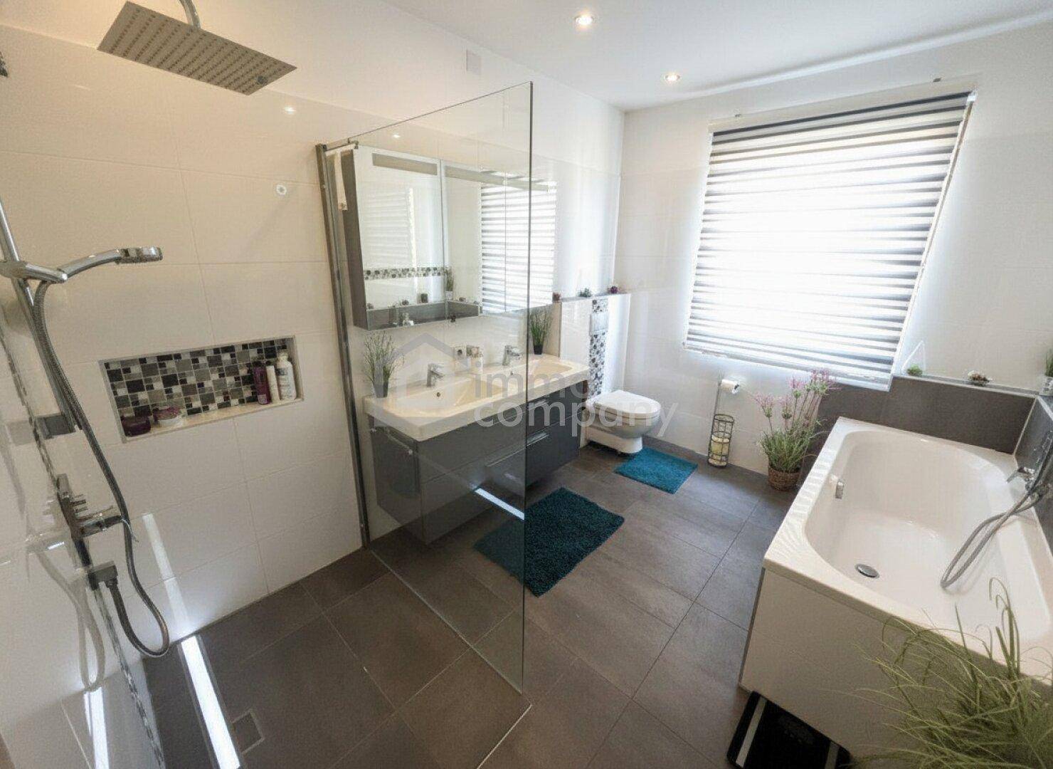 Helles Badezimmer mit Badewanne, begehbarer Dusche, Doppelwaschbecken und Fenster.