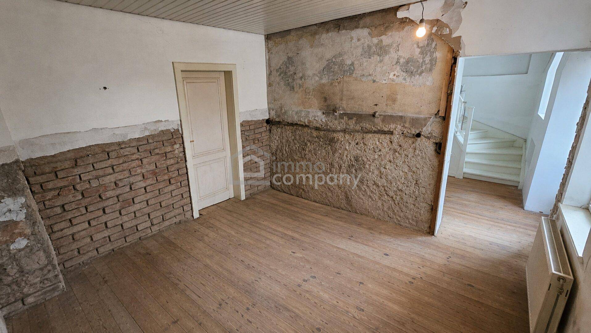Raum in Renovierung mit freigelegten Ziegelwänden und altem Holzdielenboden.