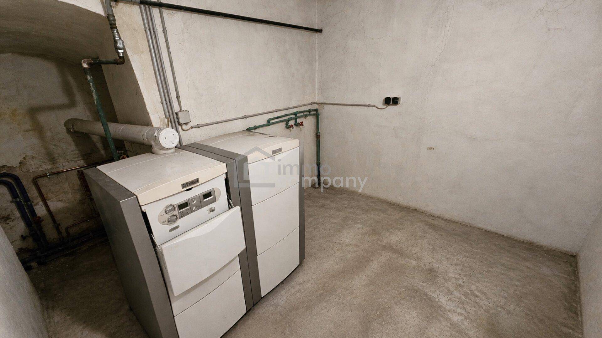 Heizungsraum im Keller mit zwei Heizkesseln und sichtbaren Rohrleitungen.