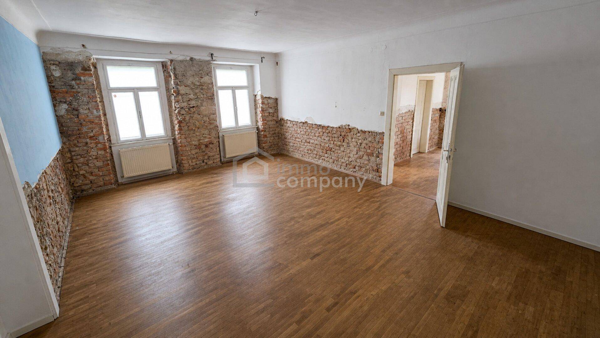 Raum in Renovierung mit freigelegten Ziegelwänden und Holzdielenboden.