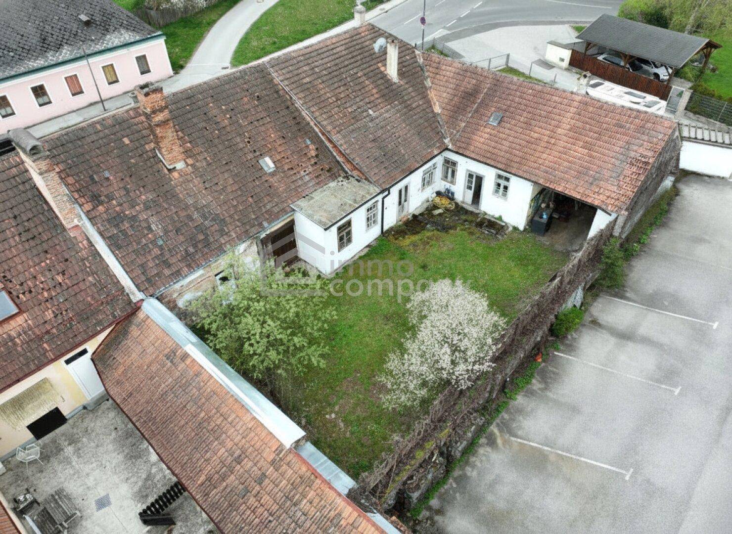 Luftaufnahme eines Innenhofs mit Grünfläche, Bäumen und angrenzenden Gebäuden.