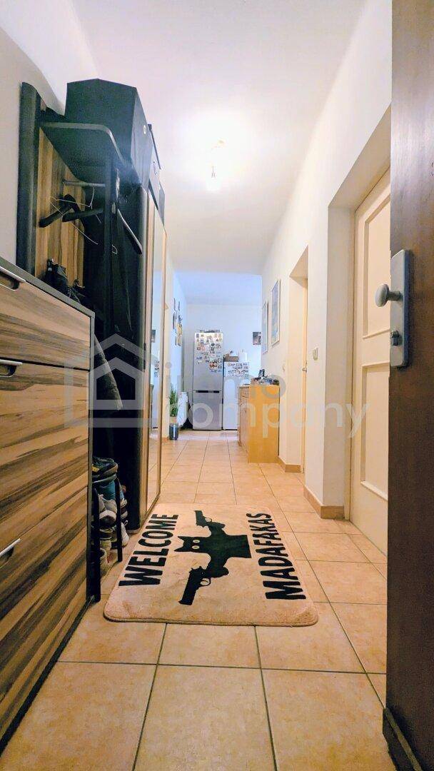 Geräumiger Flur mit Fliesenboden, Garderobe und einem Teppich, der den Eingangsbereich schmückt.