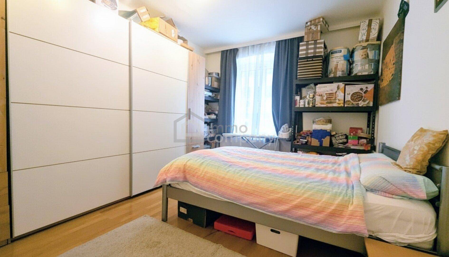 Schlafzimmer mit großem weißen Kleiderschrank, Bett und praktischen Regalen für Stauraum.