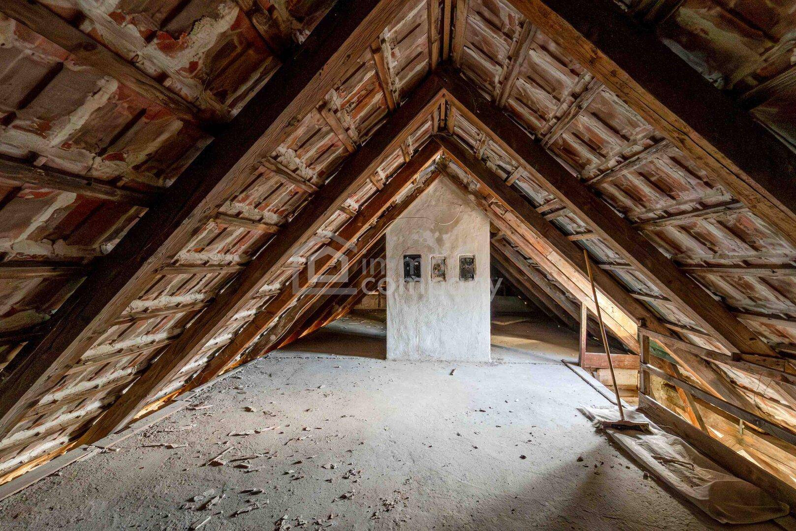 Unausgebauter Dachboden mit freiliegendem Dachstuhl und Ziegeln, bereit zum Ausbau.