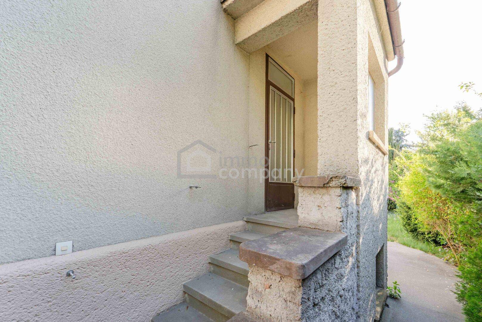 Eingangsbereich des Hauses mit Steinstufen und einer braunen Haustür.