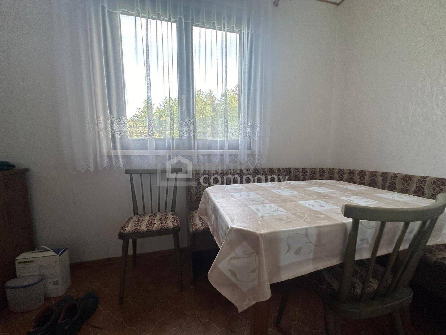 Traditioneller Essbereich mit Holztisch, Stühlen und einer Eckbank, mit Blick ins Grüne.