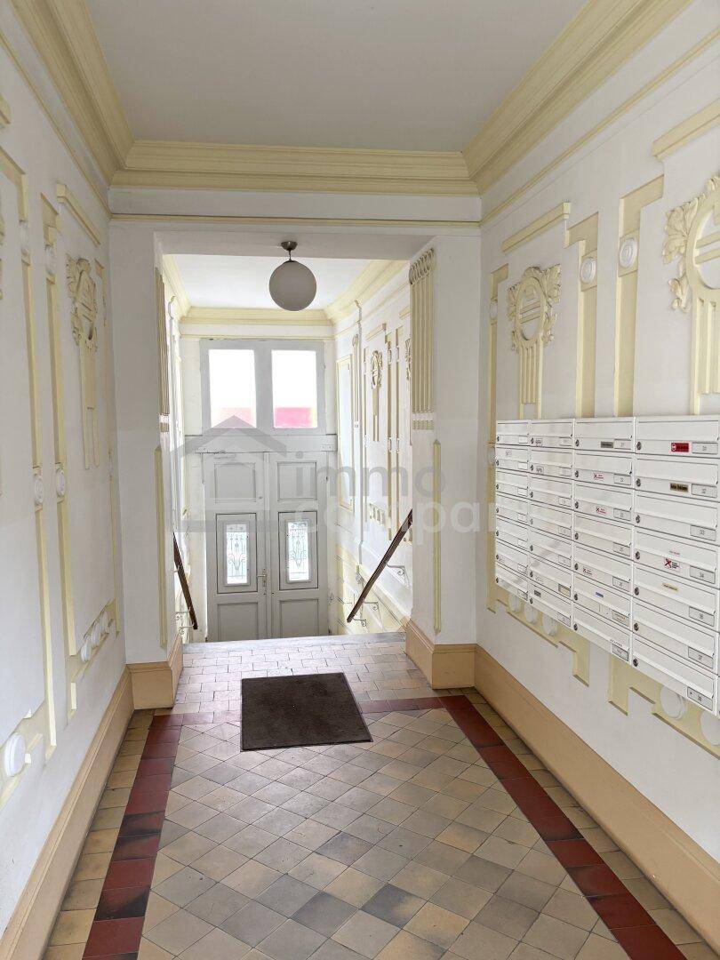 Historischer Eingangsbereich eines Altbaus mit gemustertem Fliesenboden und Briefkästen.